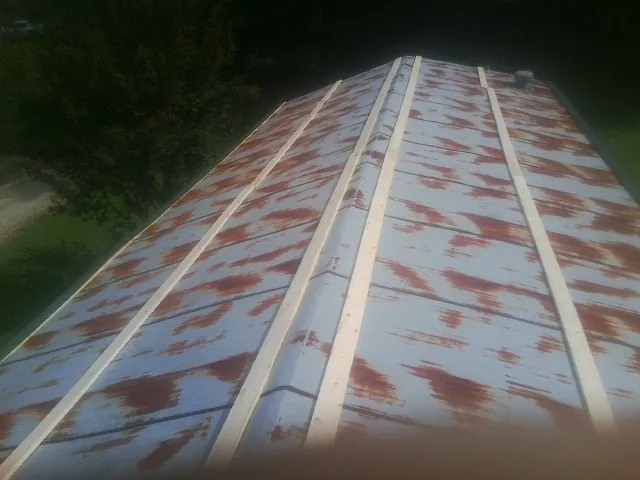 Rusted metal roof panels with new wood purlins before replacement — Storm Damage Roof Repair in Hollow Rock by Roofing Brothers
