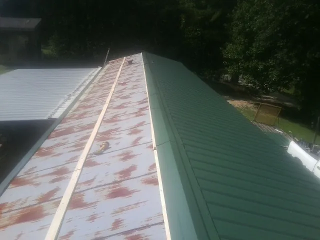 Old rusted panels beside newly installed green metal roofing — Wind Damage Roof Repair by Roofing Brothers in Hollow Rock