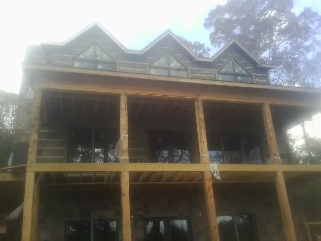 Dormers and porch framing on a large log home under construction — Roof Coating work by our crew in Hollow Rock