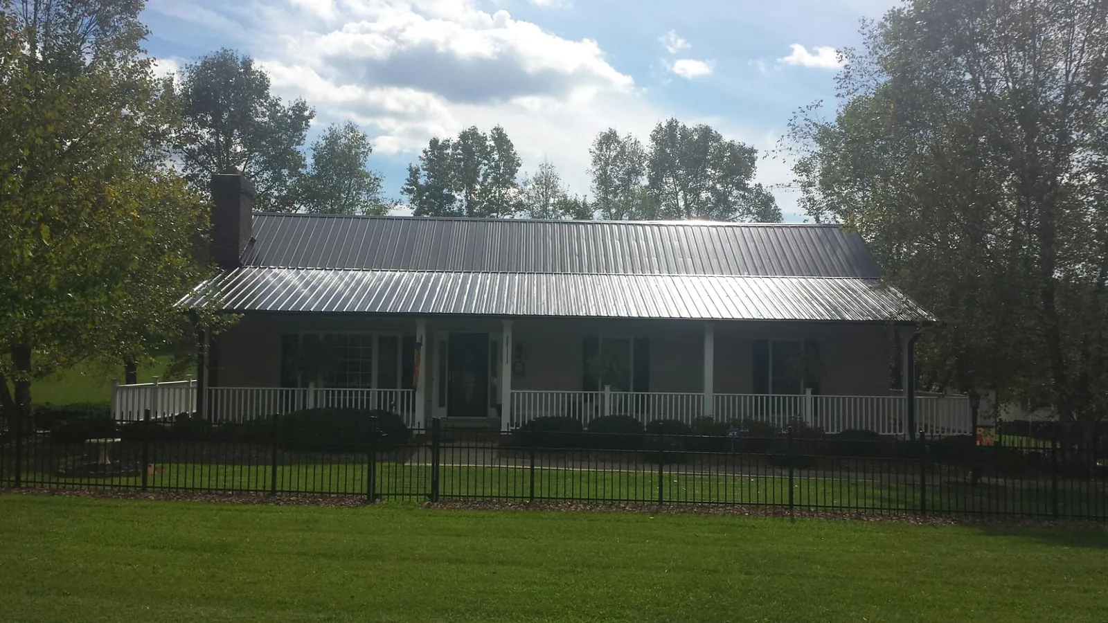 Gray metal roof on a brick ranch with a full width front porch — Gutter Guard Installation work by our crew in Hollow Rock
